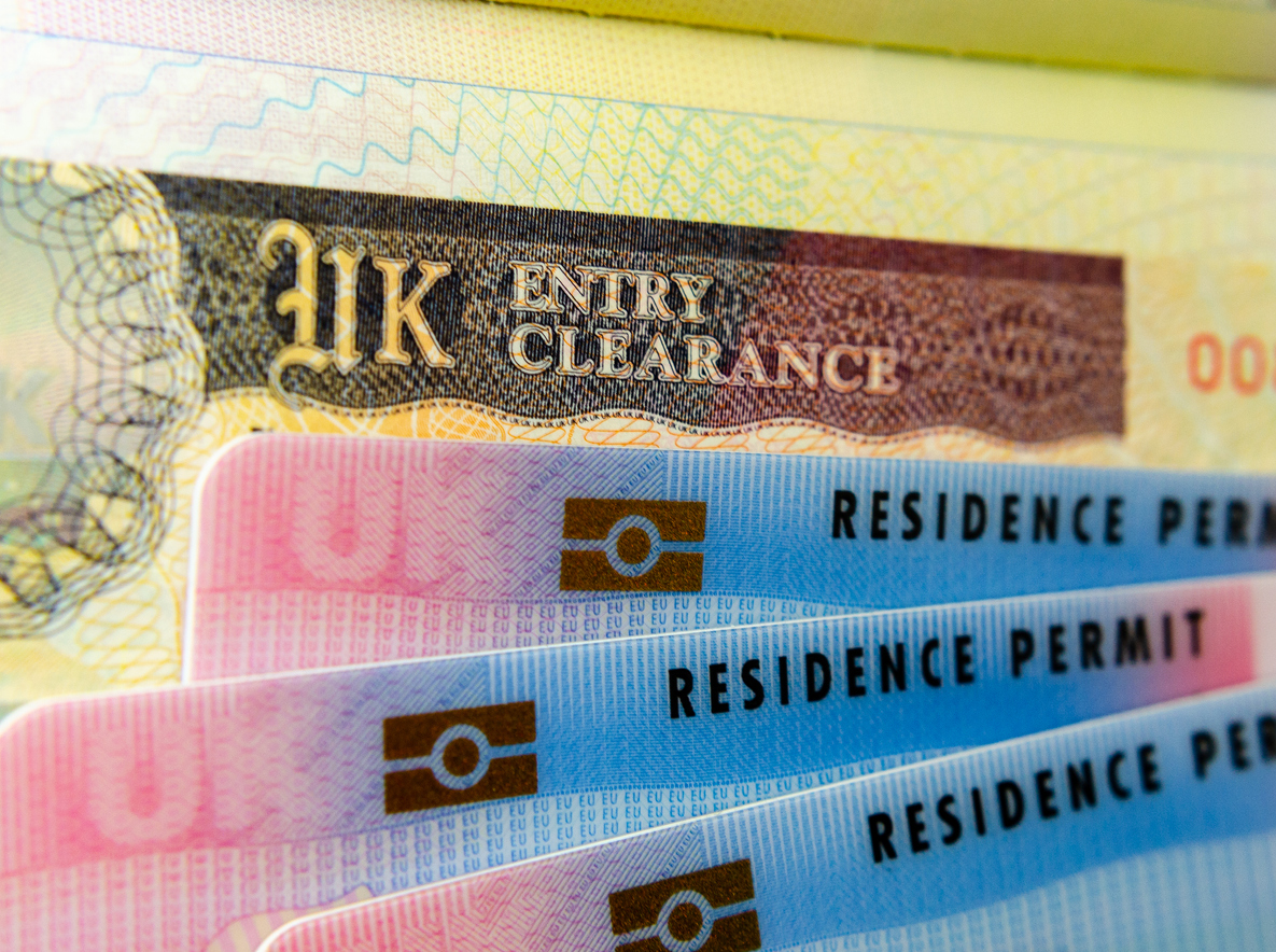 UK BRP (Biometrical Residence Permit) cards for Tier 2 work visa placed on top of UK Entry Clearance vignette sticker in the passport.