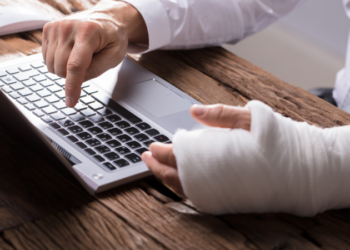 man with injured arm typing on laptop